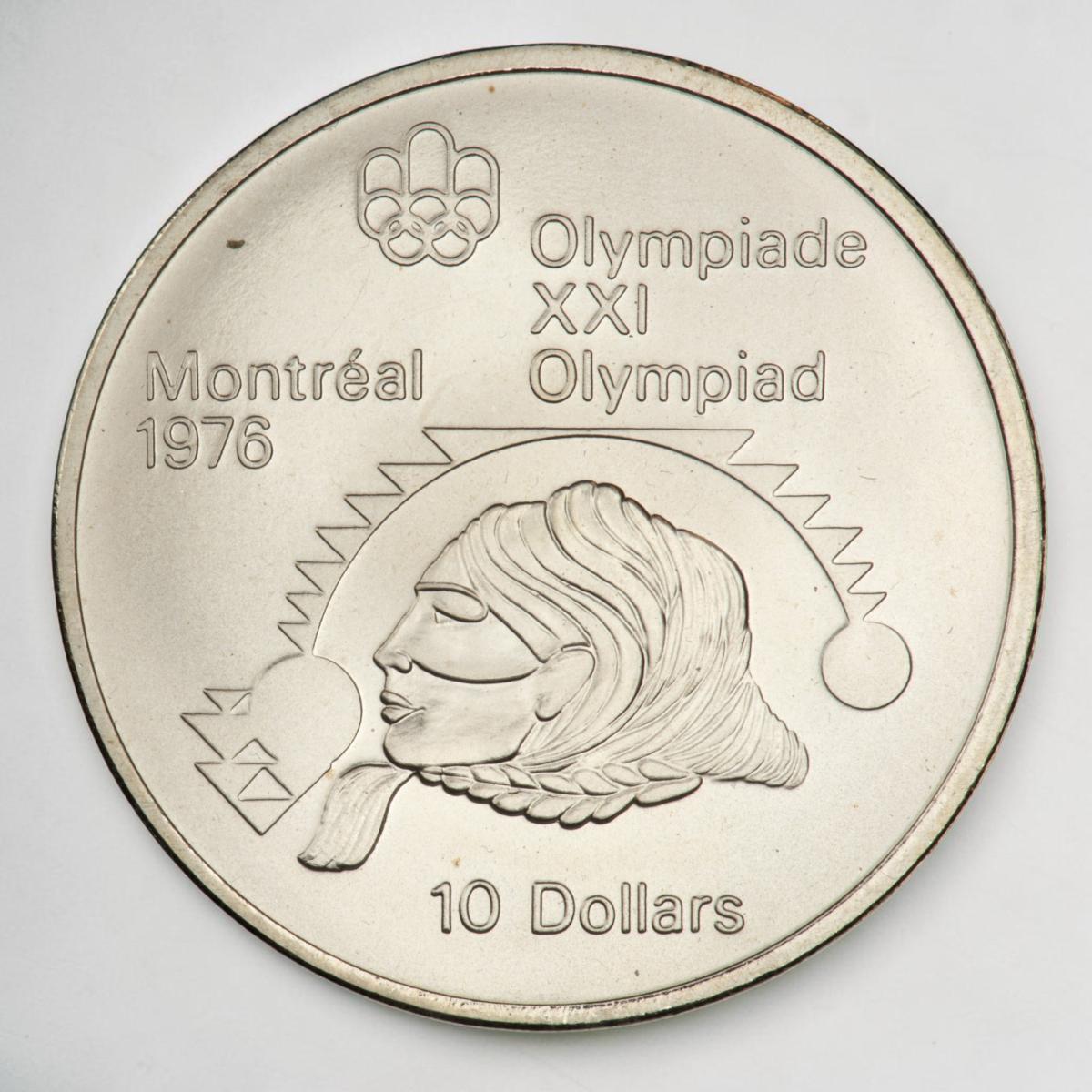Coin, silver, Indigenous person’s head, zigzag motif above, with circles at  each end.