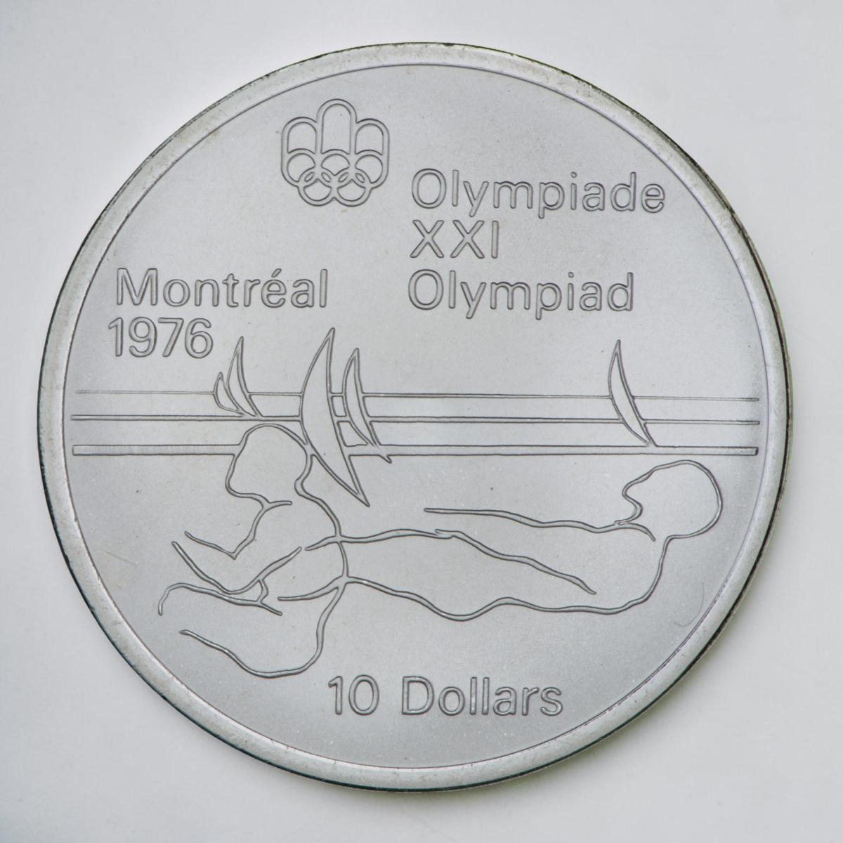 Coin, silver, stylized outline of two athletes leaning back to balance an invisible sailboat.
