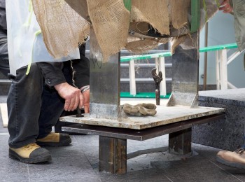 hands inserting bolts through a metal plate