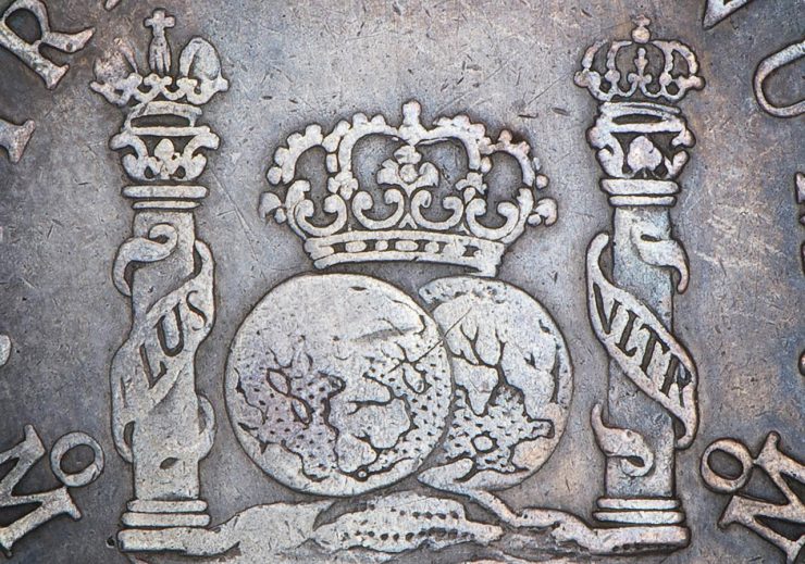 old coin showing pillars, globes and crowns