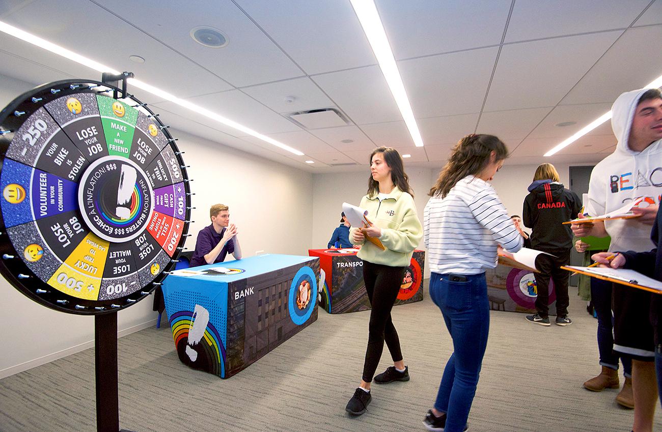 students dealing with one another in a room of brightly decorated tables students dealing with one another in a room of brightly decorated tables