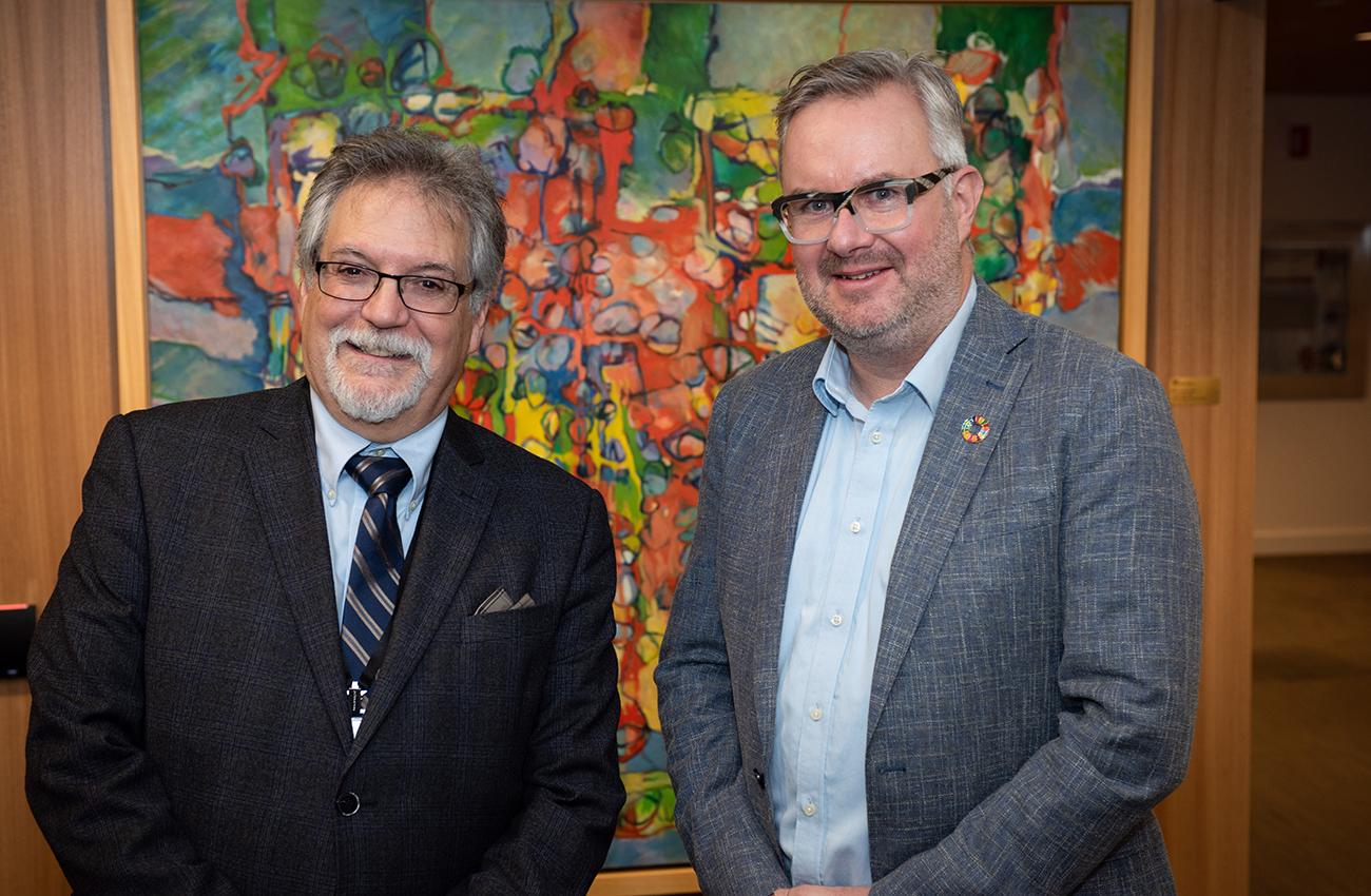 portrait of two men standing in front of a painting portrait of two men standing in front of a painting