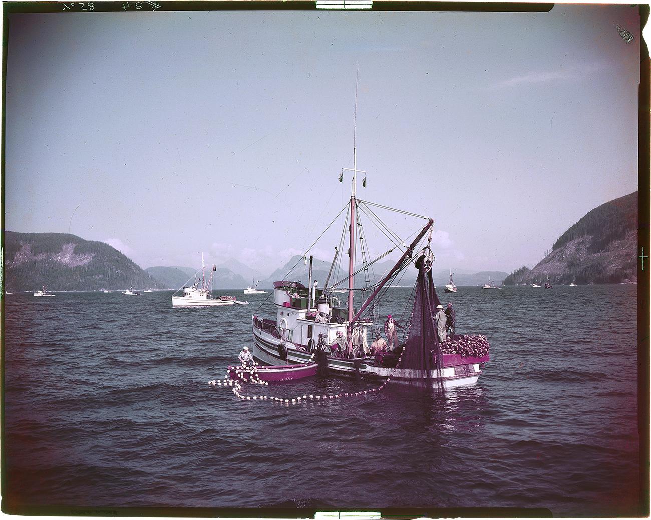 colour picture of a fishing boat on ocean near mountains