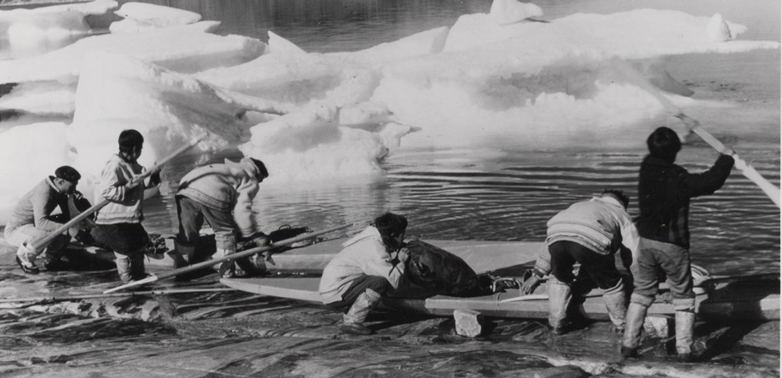 Black and white photo of six Inuit men loading kayaks.