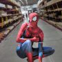 Man in a superhero costume crouching in an aisle of a home renovation warehouse.