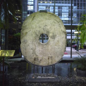 Large, roughly carved oval stone with a hole in the centre.