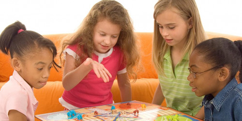 A diverse group of 4 young children playing a board game.