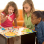 A diverse group of 4 young children playing a board game.