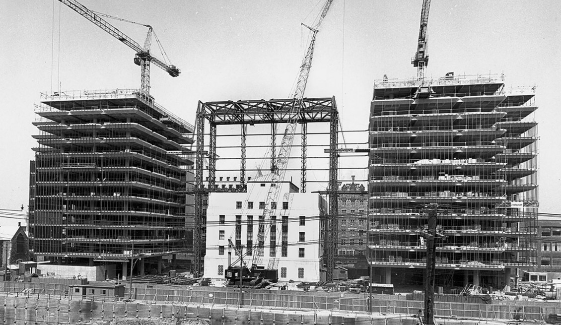 Building, old stone bank surrounded by skeletal, half-finished structures.