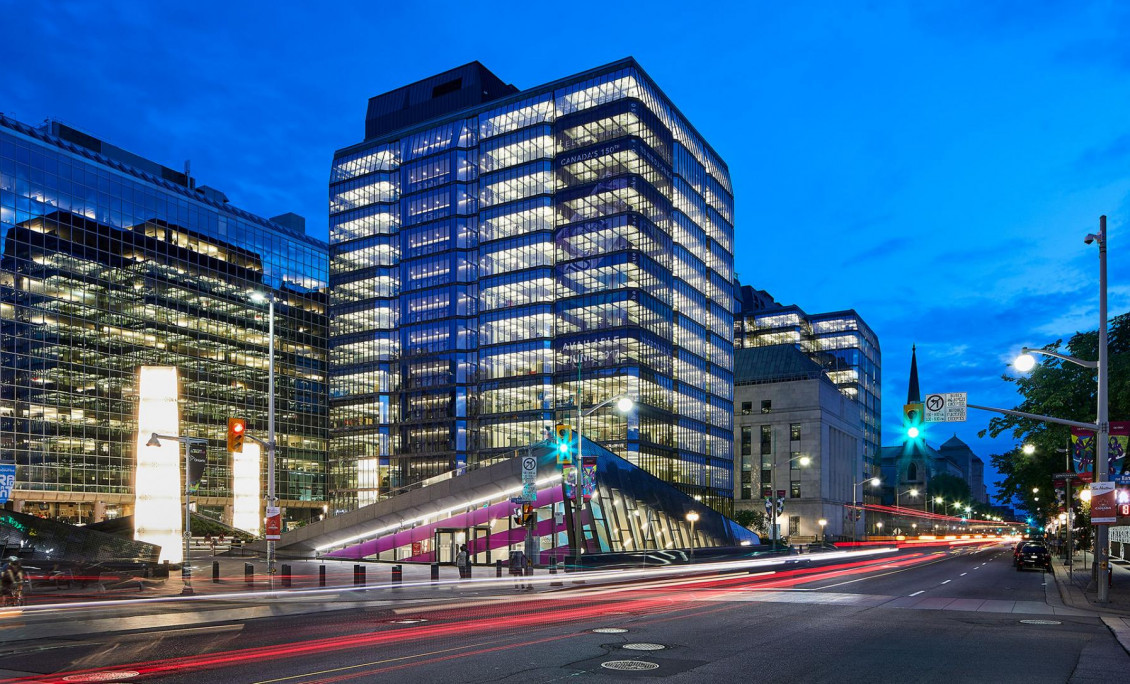 Building, illuminated glass towers on either side of an old, square, stone building.