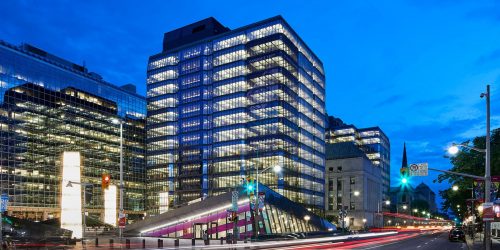 Building, illuminated glass towers on either side of an old, square, stone building.