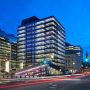 Building, illuminated glass towers on either side of an old, square, stone building.