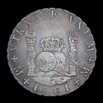 Silver coin of 8 reales, reverse side showing 2 pillars wrapped in banners and 2 globes topped with a crown.