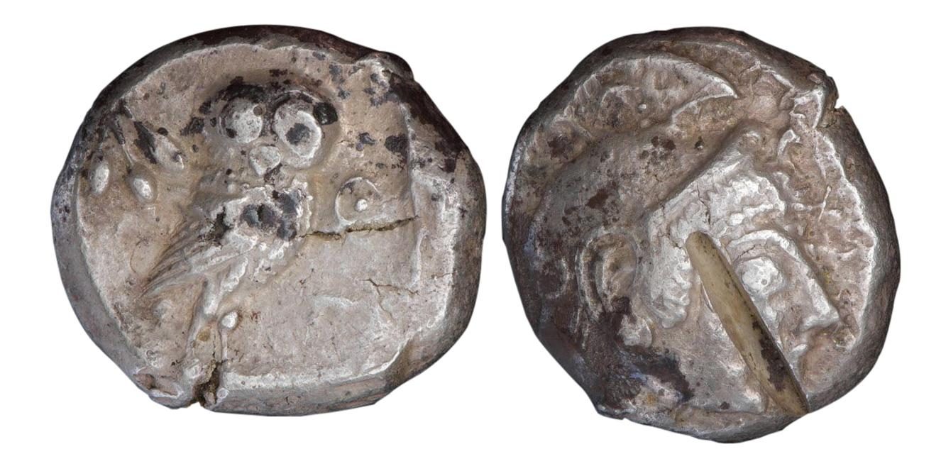 Coin, 2 sides, owl on one side other side with a deep cut in the surface.