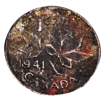 Coin, penny, details obscured by crusty brown coating.