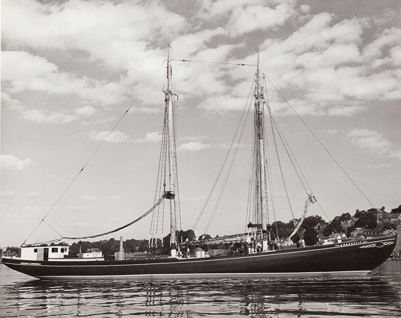 Photo, black and white, a 2-masted sailing ship, a schooner, long and sleek, low and black.