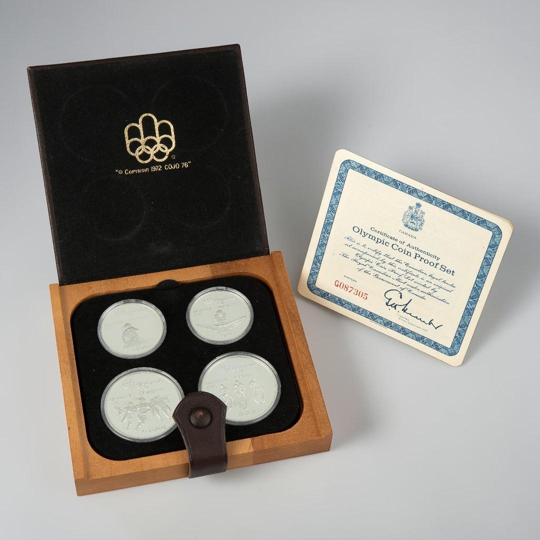 Leather case, square, flat, holding four silver coins all alongside a certificate.
