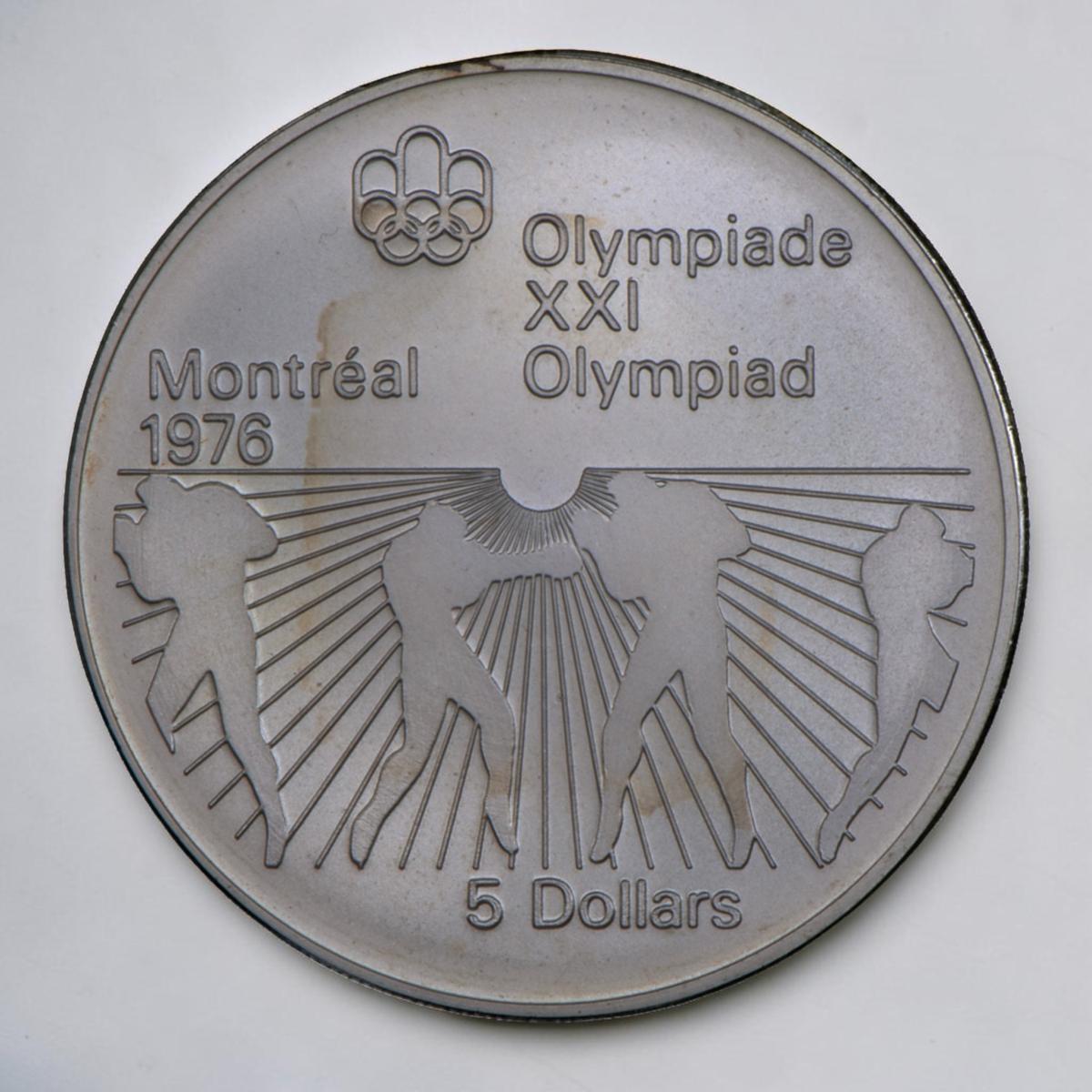 Coin, silver, sunburst pattern on bottom half with outlines of figures punching one another with round gloves on.