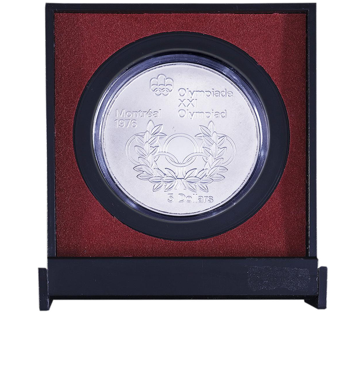 Red and black plastic case holding a silver coin with a logo of linked rings and a wreath.