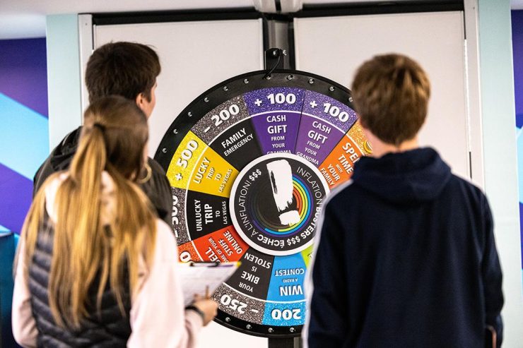 Spinning a wheel Two people with clipboards turning a colourful, roulette-style wheel.