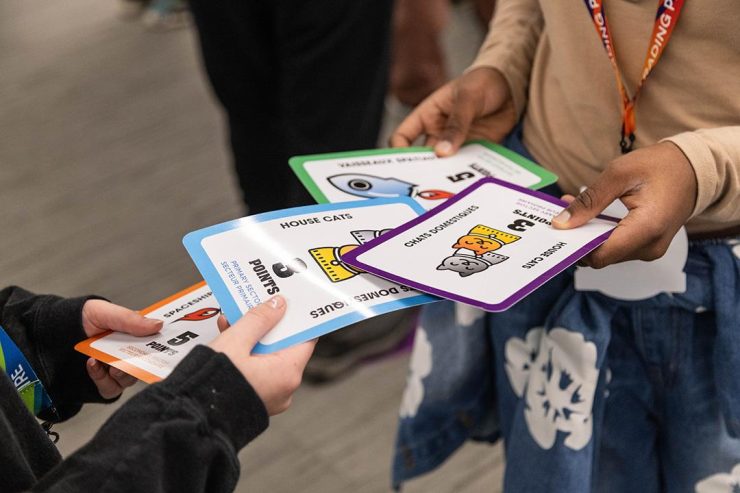 Trading game cards Children’s hands laying down brightly coloured game cards with cartoon images on them.